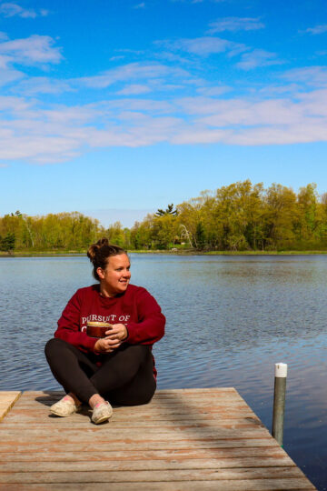 Antonia, the Minnesota mom behind Knead to Roam, sitting on a dock in Wisconsin.
