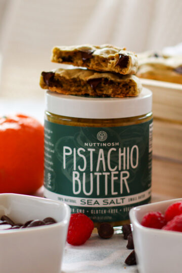 Pistachio Butter Chocolate Chip Cookies surrounded by fruit and chocolate chips.