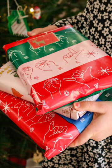 A young girl holds a pile of gifts.