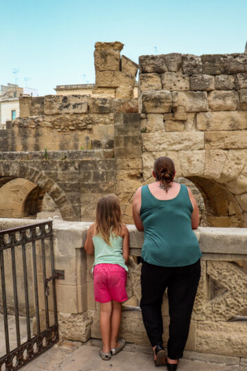 A mom and her young daughter enjoy a view into the Roman amphitheater in Lecce.