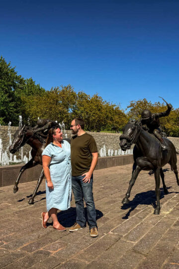 Antonia and her husband in front of horse statues in Lexington.