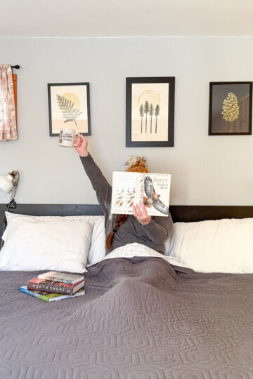 Antonia holds a coffee while reading in bed at Basecamp Bungalows.