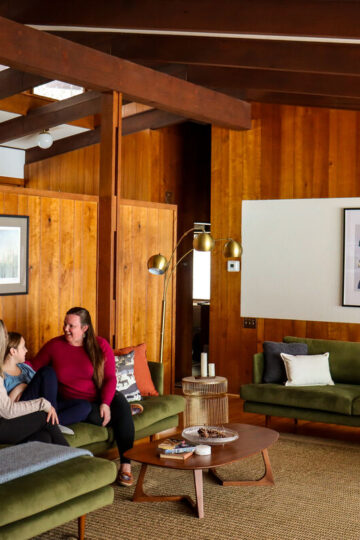 Three generations of women chat on a couch in a cozy cabin in Grand Rapids.