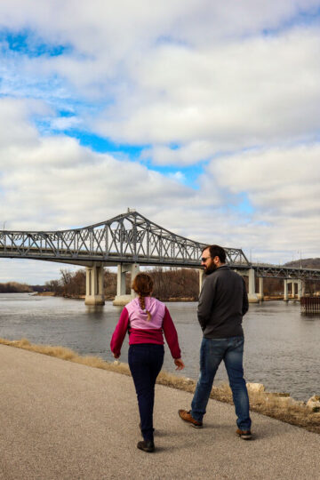 A father and his young daughter walk along a paved path in Winona.