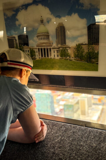 A young girl looks out a window at the top of the Gateway Arch.