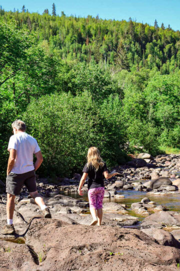 A young girl and her grandfather walk along the rocks in Temperance River State Park.
