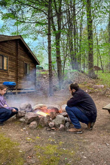 A man and his young daughter make s'mores on the fire while staying at Wildman Adventure Resort.
